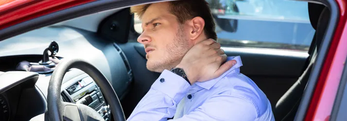 Chiropractic Northfield MN DOT A man sitting in a car, holding his neck in pain, indicating a possible injury from a car accident.